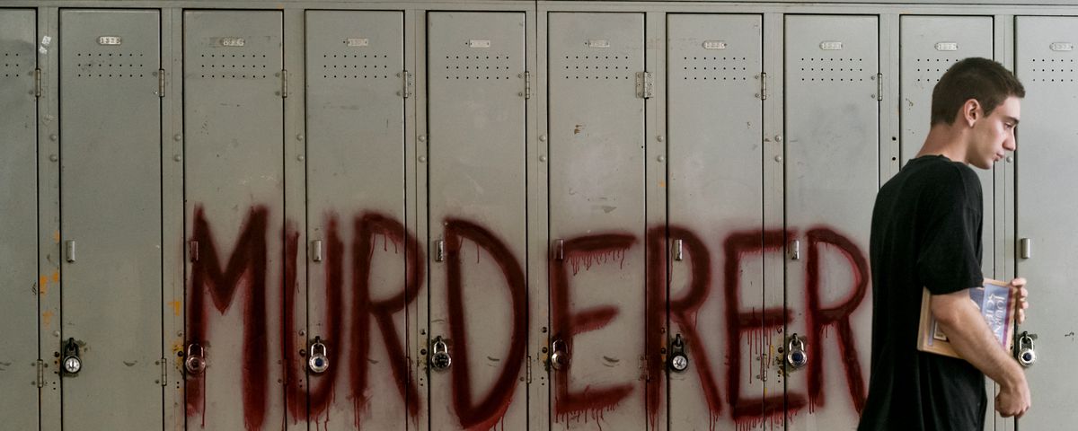 Theodore Pellerin walks past a bank of grey school lockers with “MURDERER” scrawled across them in red paint in There’s Someone Inside Your House
