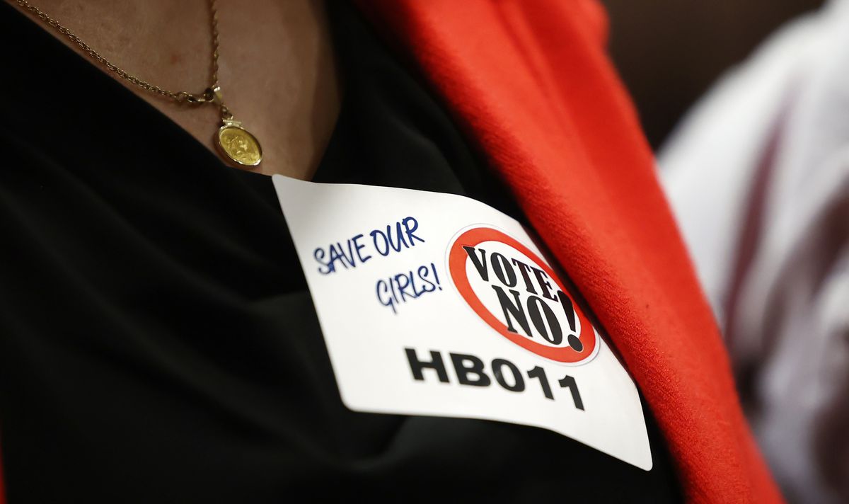 A woman wearing a sticker opposing a transgender girls sports bill sponsored by Rep. Kera Birkeland, R-Morgan, stands in a hallway after a hearing on the bill before the Utah Legislature’s House Health and Human Services Committee at the Capitol in Salt Lake City on Monday, Feb. 14, 2022.