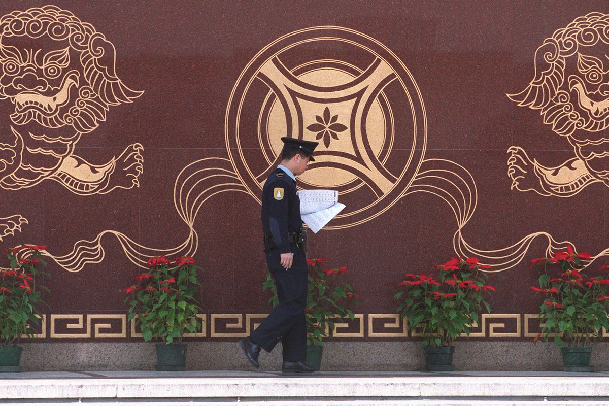 A Macau police officer carries out his duty around Jai-Alai Casino, walks past the marble carving decoration of the entertainment complex which shows lions guard a coin December 26. The entertainment complex including casinos, massage parlours, restaurant