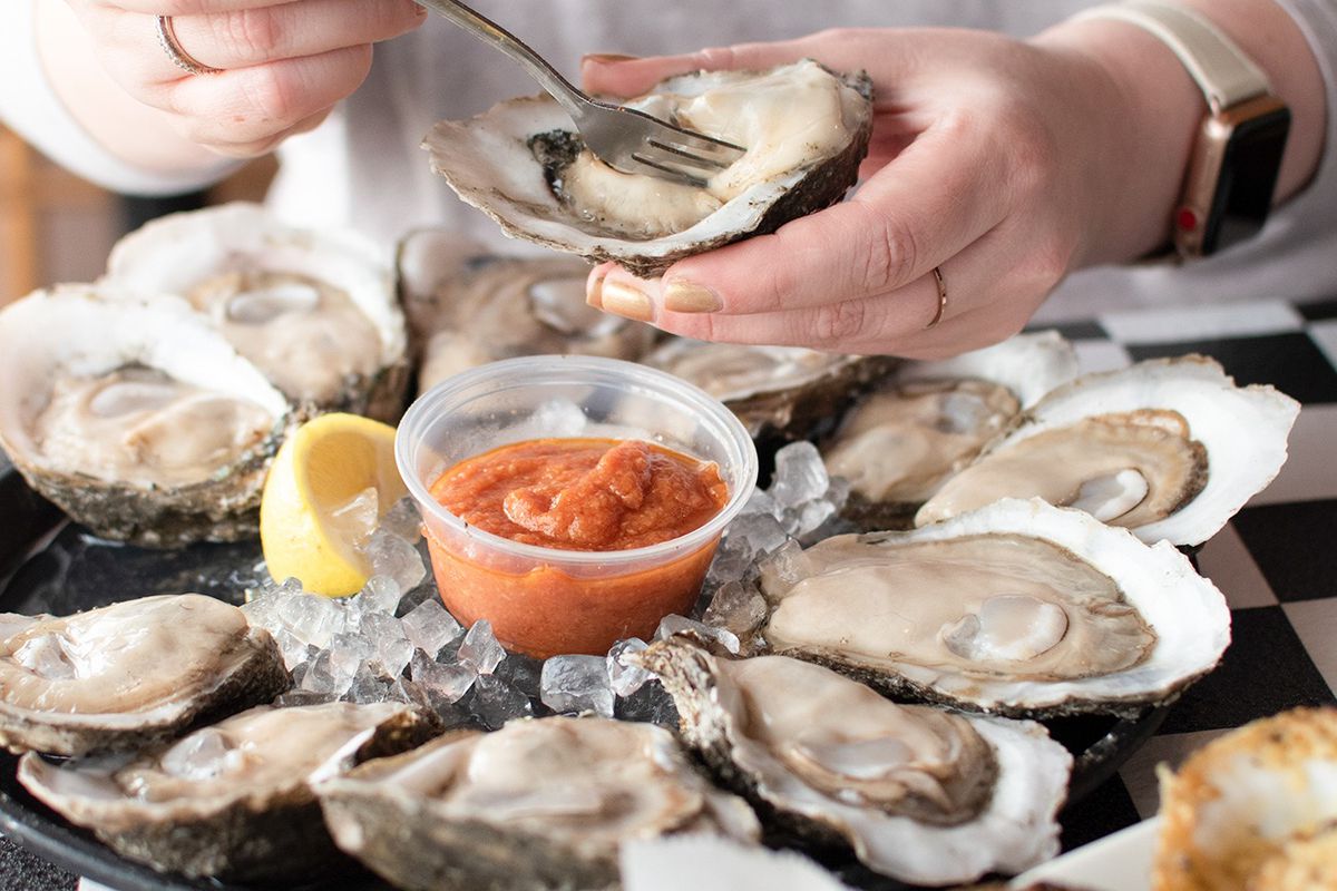 a person eating raw oysters from the halfshell with a fork