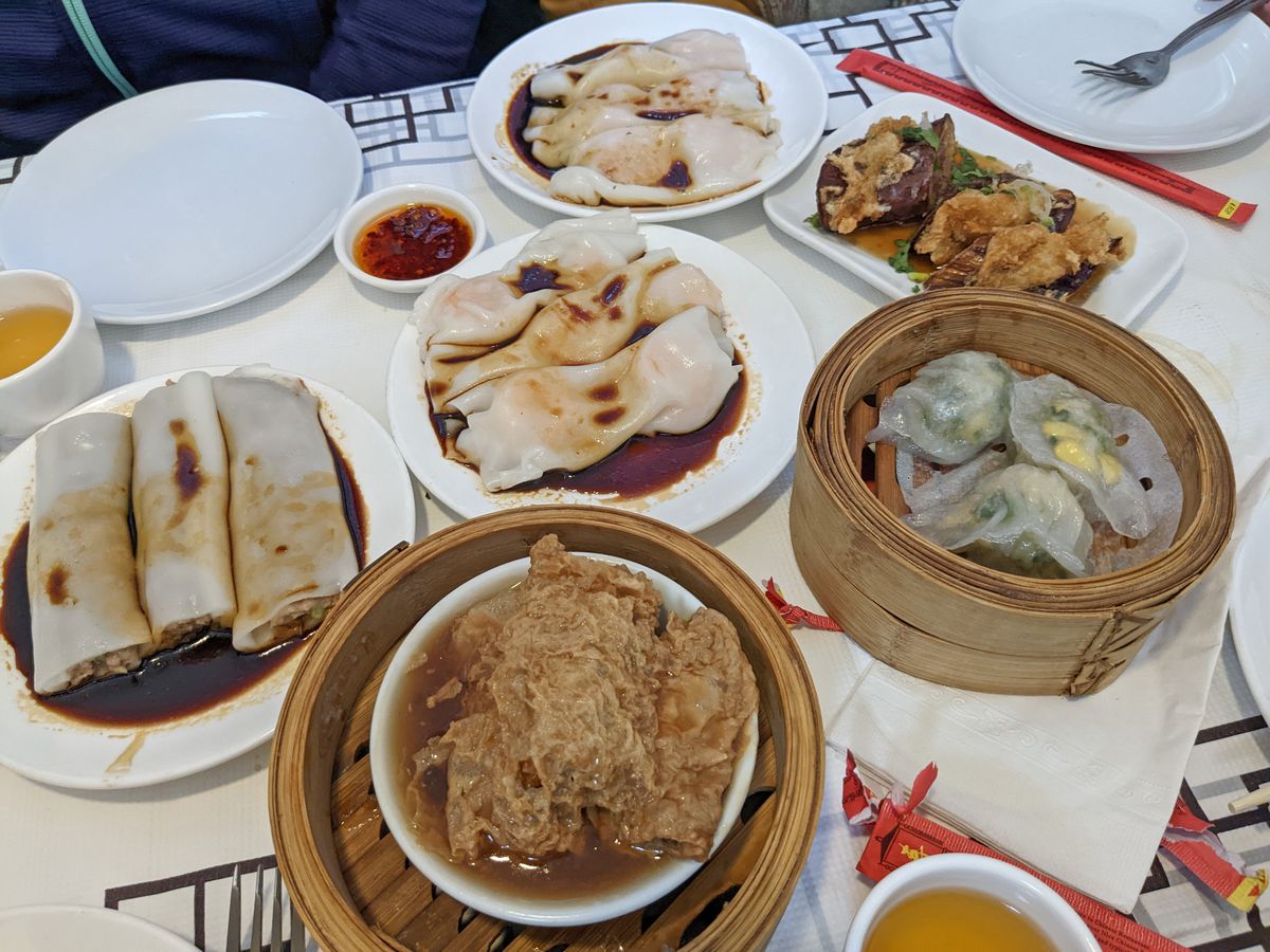 Dim sum on plates and in steamers on a white tablecloth.