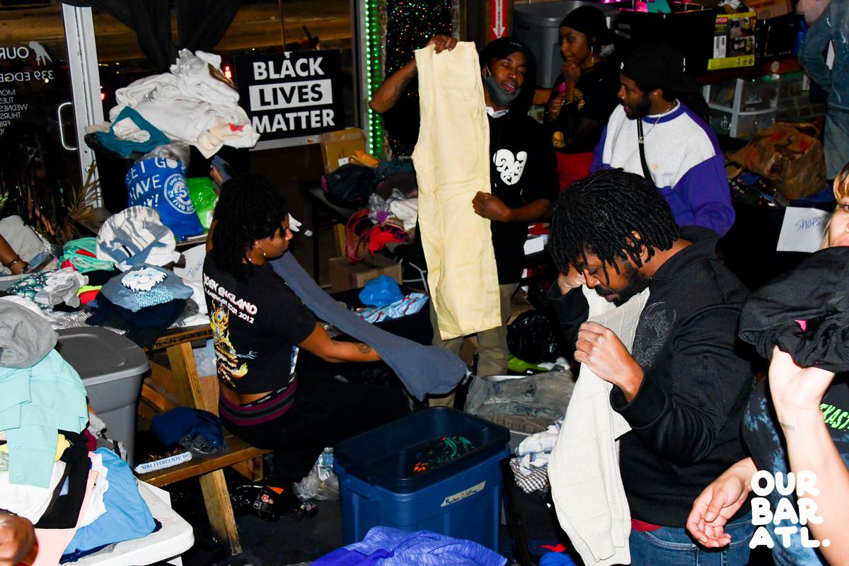 Volunteers and bar employees preparing clothing and goods to give out during Our Bar ATL’s annual Hug the Block charity event. 