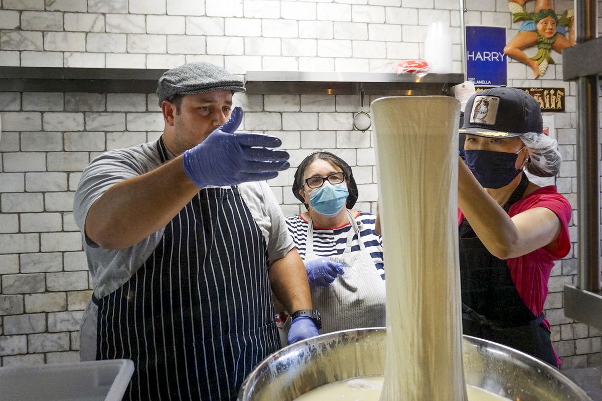 Nonnas Adelina Orazzo, center, and Yumi Komatsudaira, right, make fresh mozzarella with vendor Anthony Agostino on Thursday ahead of Enoteca Maria’s grand reopening.