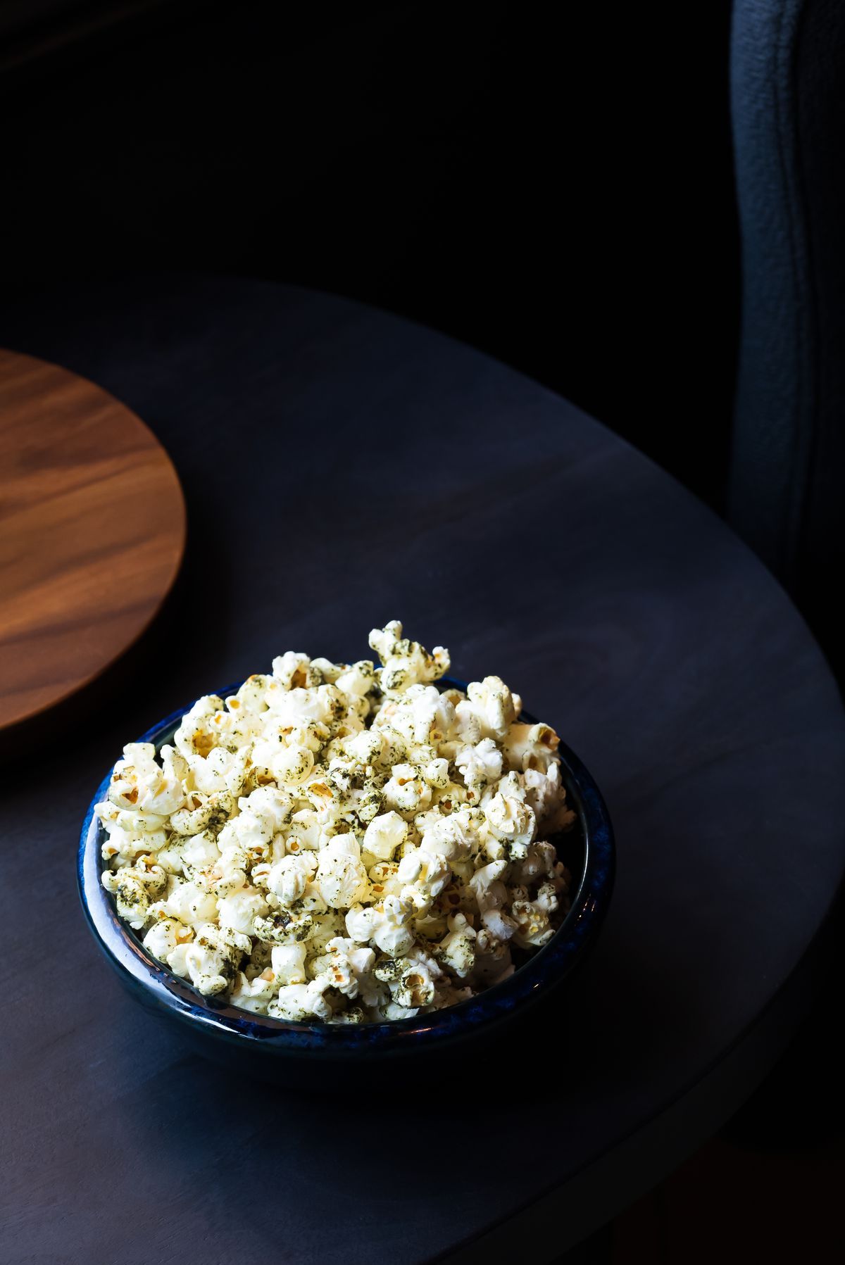 A black ceramic bowl filled with popcorn topped with furikake.