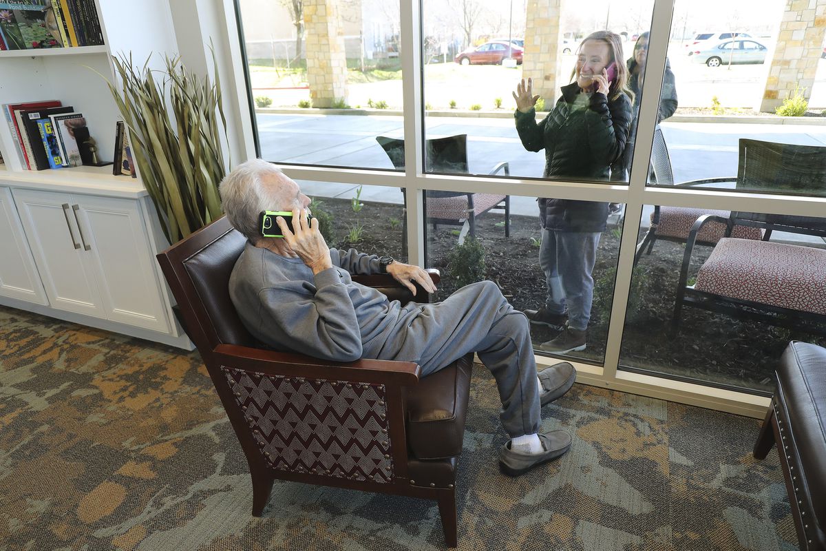 Kaye Knighton, a resident at Creekside Assisted Living and Senior Center in Bountiful, talks by cellphone to daughter-in-law Darla Knighton on Friday, March 27, 2020. Family of residents come to the window to see and talk to them via a cellphone due to Covid-19 restrictions.