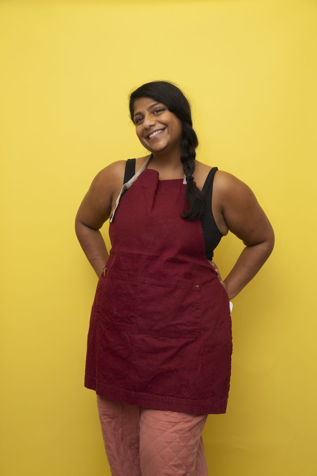 A woman in a red apron in front of a yellow background.
