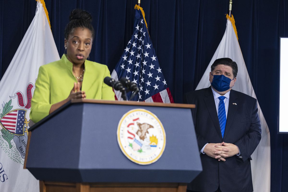 Gov. J.B. Pritzker listens as state Public Health Director Dr. Ngozi Ezike briefs the media in May.