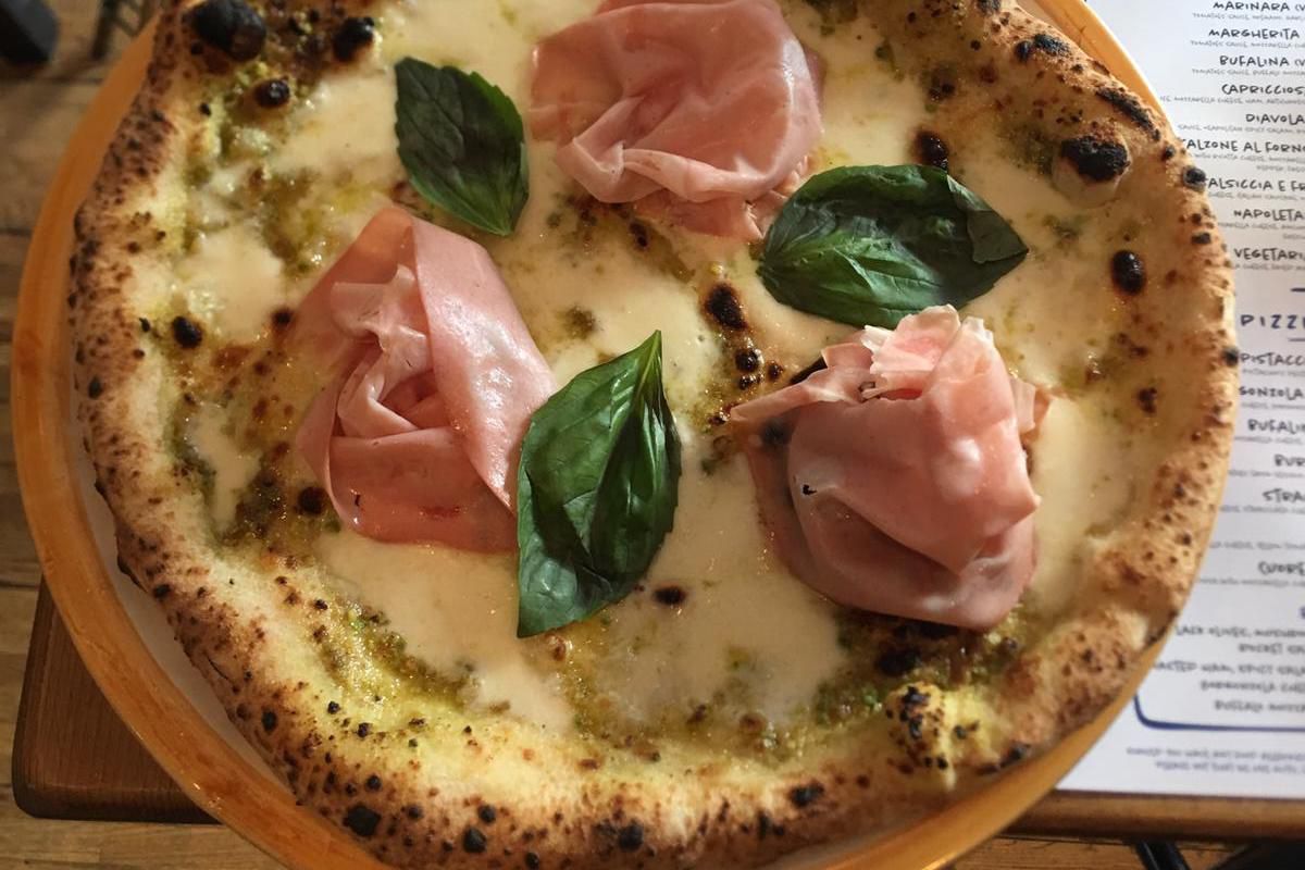 Mortadella, basil, and cheese on a pizza seen from a birdseye view, at Pizzeria Pellone