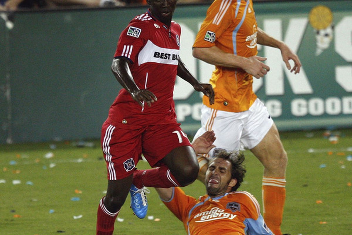 HOUSTON - AUGUST 21:  Patrick Nyarko #14 of the Chicago Fire leaps over a sliding Brian Mullan #9 to avoid the tackle in the first half at  Robertson Stadium on August 21 2010 in Houston Texas.  (Photo by Bob Levey/Getty Images)