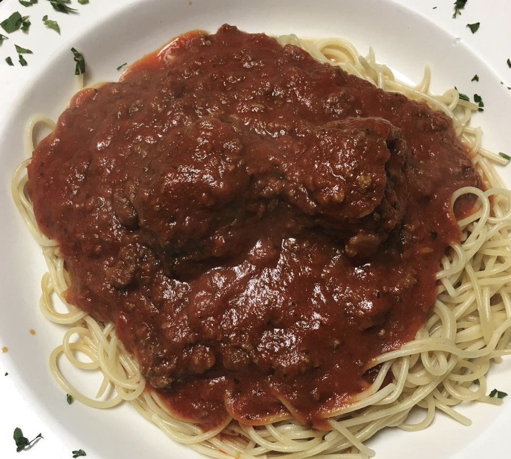 A top down view of a messy plate of spaghetti and meatballs.