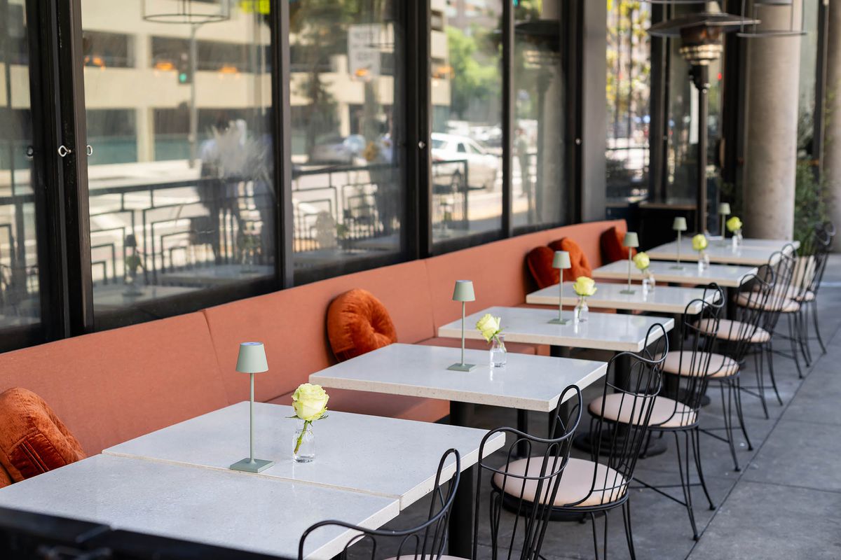 Off-white marble tables and peach seats at a new daytime patio restaurant named Joyce in Los Angeles.