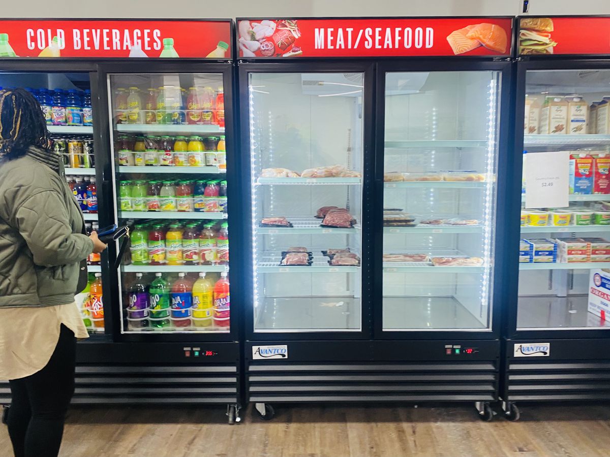 Three refrigerated sections carrying beverages, meat, and dairy products at Neighborhood Grocery in Detroit, Michigan.