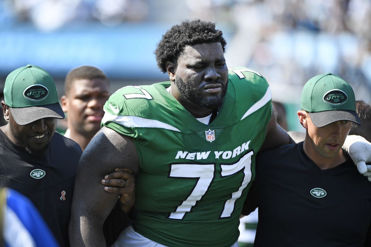 Mekhi Becton #77 of the New York Jets is helped off the field after being injured during the third quarter against the Carolina Panthers at Bank of America Stadium on September 12, 2021 in Charlotte, North Carolina.