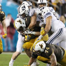 The Brigham Young Cougars defense tackle Wyoming Cowboys running back Brian Hill (5) during the Poinsettia Bowl in San Diego on Wednesday, Dec. 21, 2016. BYU won 24-21.