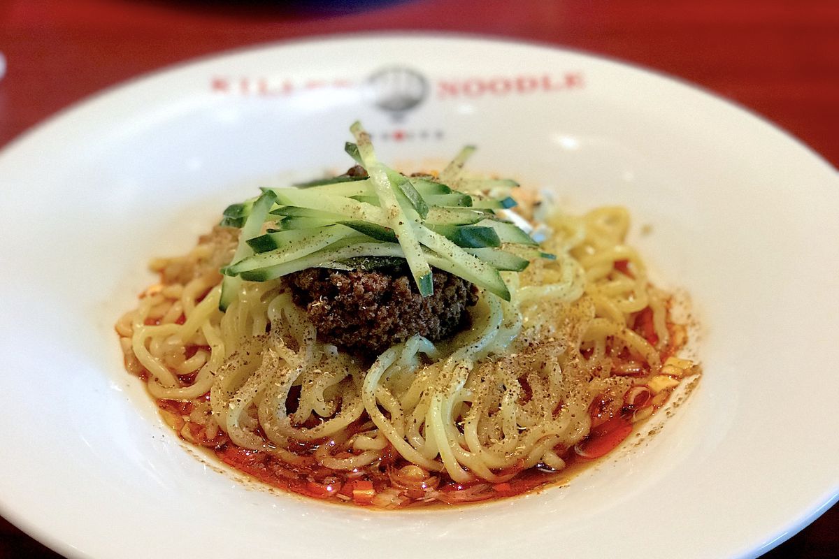 A spicy bowl of noodles on a red table.
