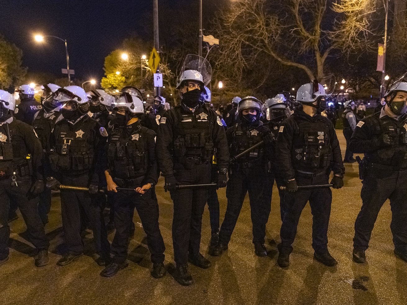 Chicago police form a line with batons out after an earlier clash with protesters near Logan Square Park in Chicago Friday, April 16, 2021, a day after the release of video that shows a Chicago police officer fatally shoot a 13-year-old last month.