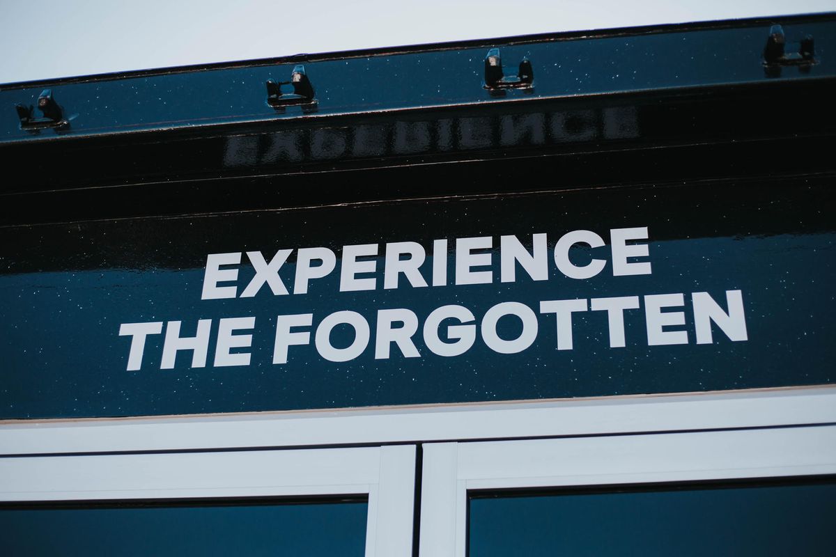 Above the entrance, a sign reads, “Experience the Forgotten.”