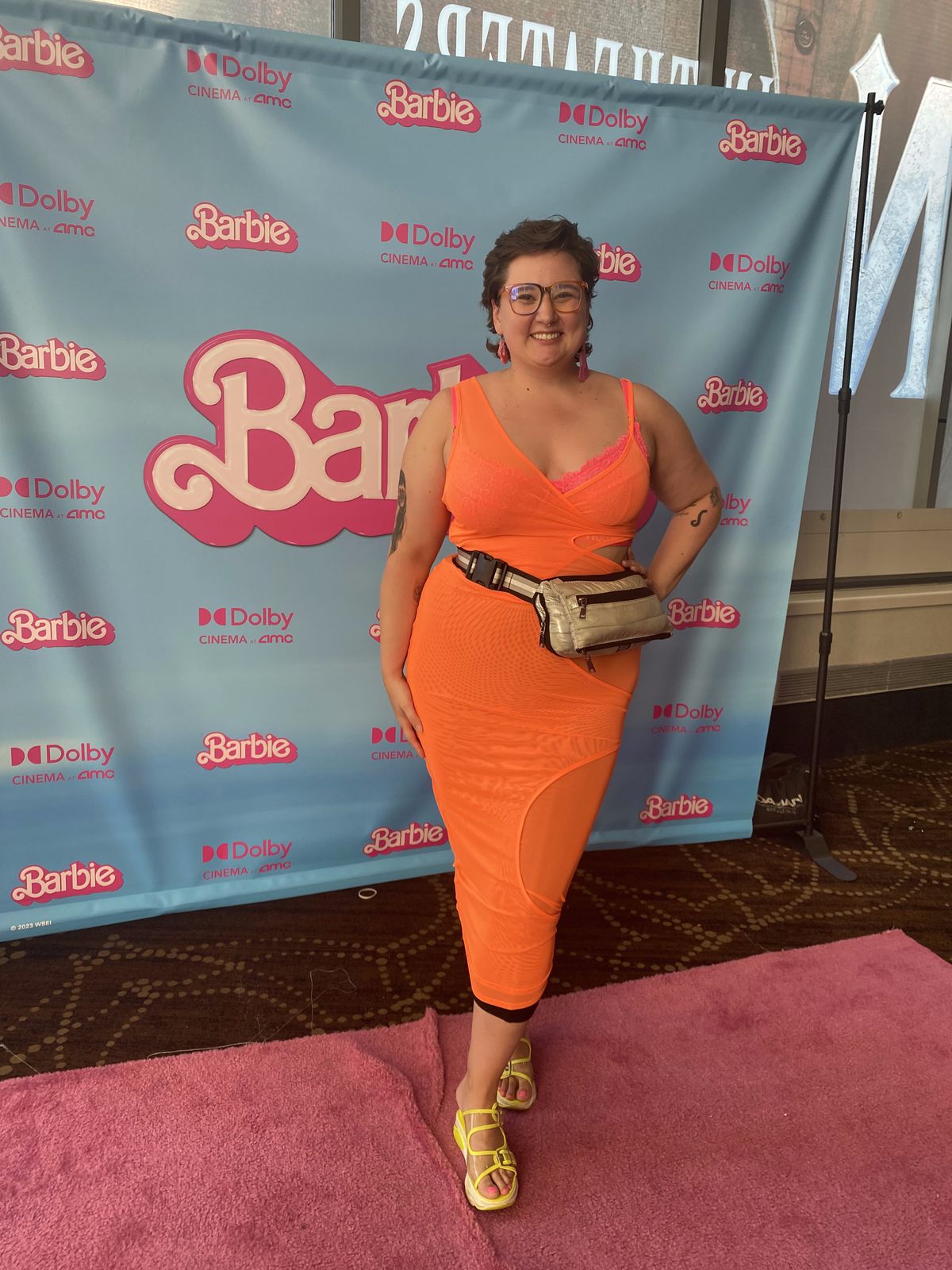 A person in a bright orange dress getting ready for Barbie