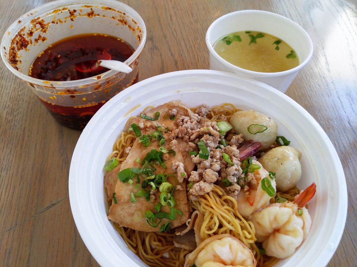 A bowl of noodle soup with shrimp, pork, and fish balls, with broth and chile oil in separate bowls, above.