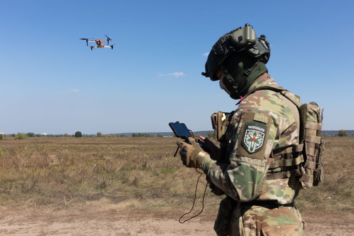 A drone operator launches a quadcopter to monitor the operation of an evacuation robot during its field testing.