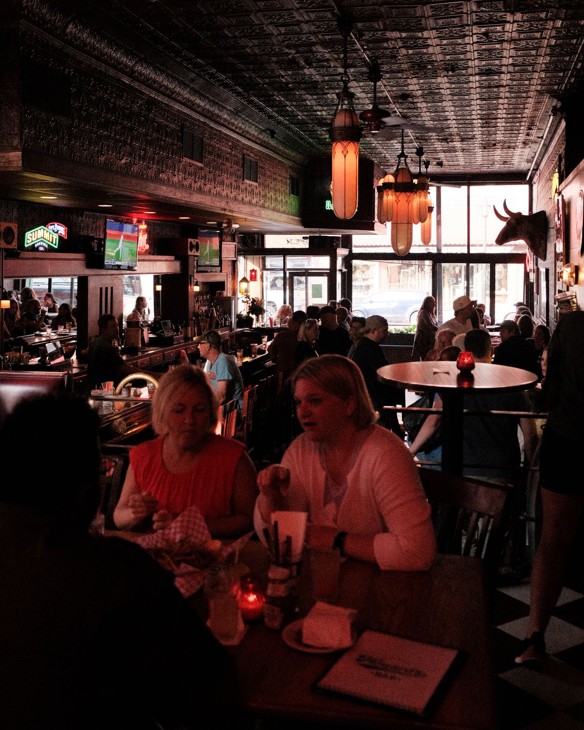 People sitting at a table; the interior of a darkened bar in the background. 