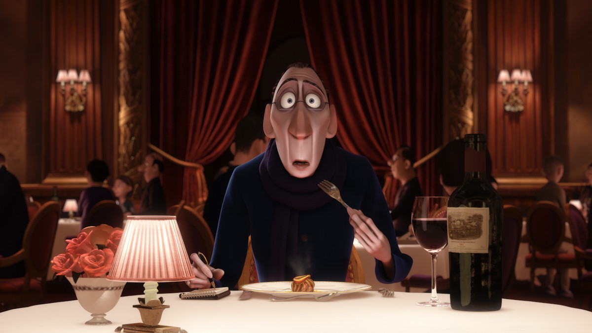 The shocked animated character of Anton Ego holds a fork mid-bite, mouth agape, while seated at a tablecloth-covered table in a formal, red-draped dining room.