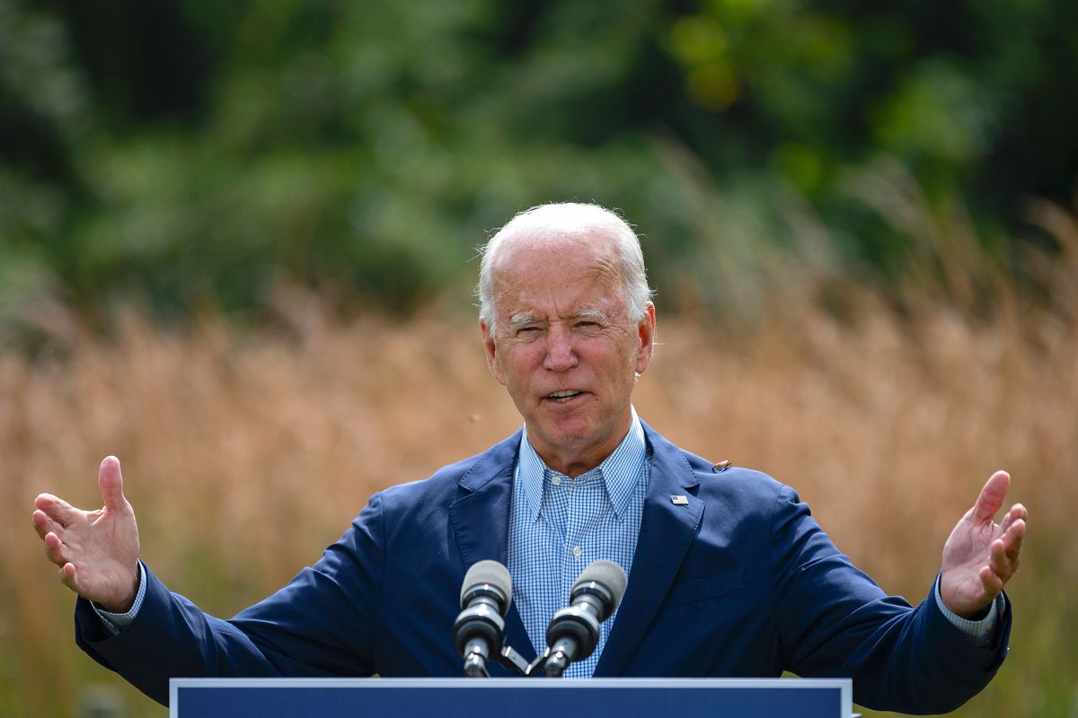 Joe Biden speaking at a lectern with a field behind him.