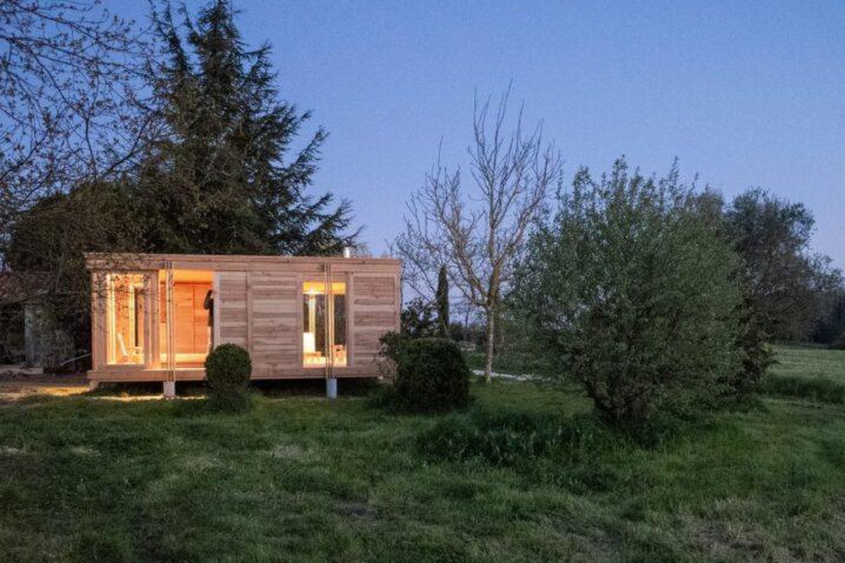 Timber tiny house glowing at dusk.