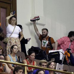 Member of the gallery respond by holding up their shoes as Sen. Wendy Davis, D-Fort Worth, is called for a third and final violation in rules to end her filibuster attempt to kill an abortion bill, Tuesday, June 25, 2013, in Austin, Texas. The bill would ban abortion after 20 weeks of pregnancy and force many clinics that perform the procedure to upgrade their facilities and be classified as ambulatory surgical centers.  (AP Photo/Eric Gay)