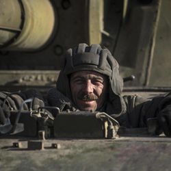 A Ukrainian soldier smiles riding on a self-propelled artillery near Artemivsk, eastern Ukraine, Monday, Feb. 23, 2015. A Ukrainian military spokesman says continuing attacks from rebels are delaying Ukrainian forces' pullback of heavy weapons from the front line in the country's east. 