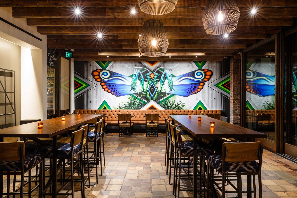 Empellon Al Pastor Midtown’s dining room has two long communal tables and a mural on the back wall.