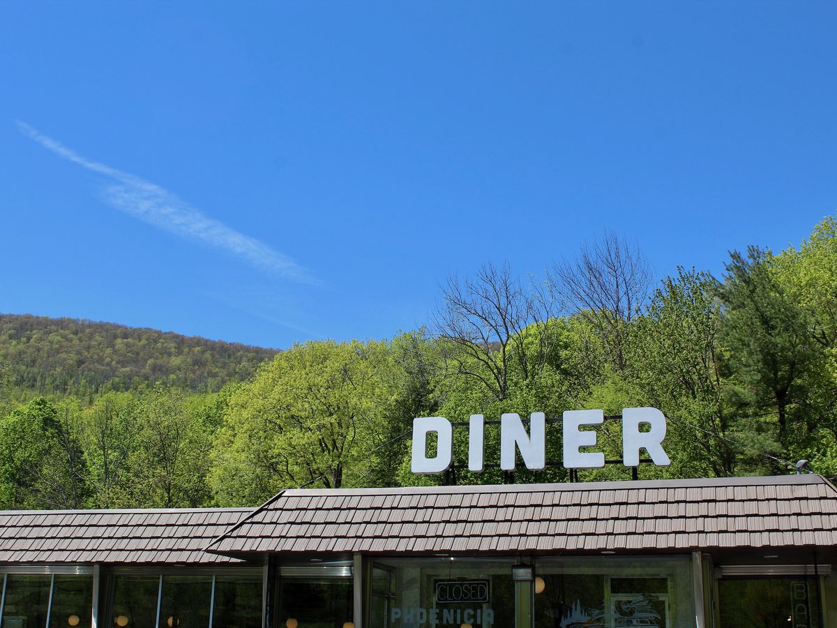A restaurant sign with mountains in the back