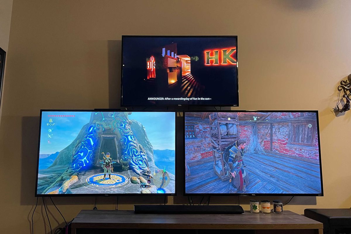 3 TVs hanging on a wall in a pyramid shape