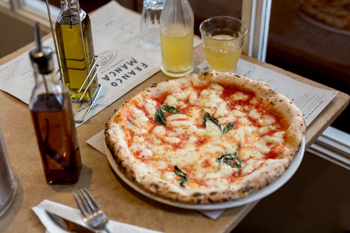 Pizza at Franco Manca on a wooden table, served on a white plate.