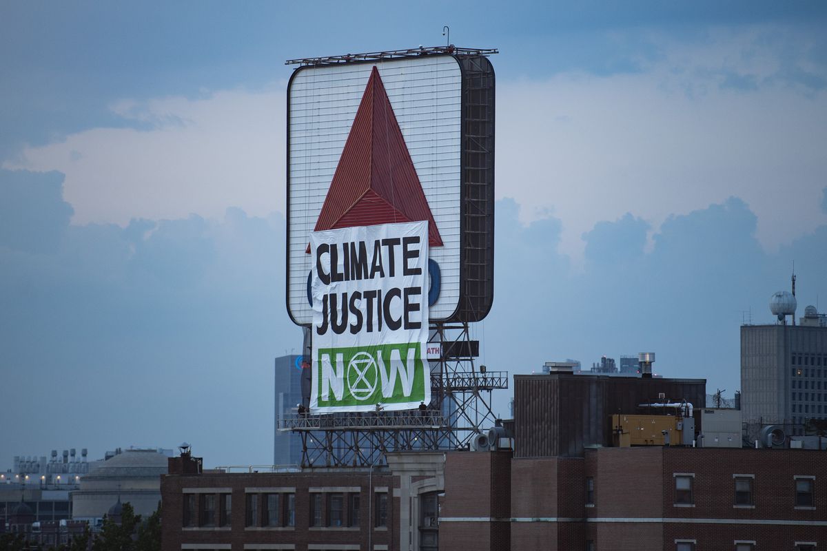 A protest banner with the words “Climate Justice Now” placed in front of the Citgo sign in Kenmore Square in Massachusetts.
