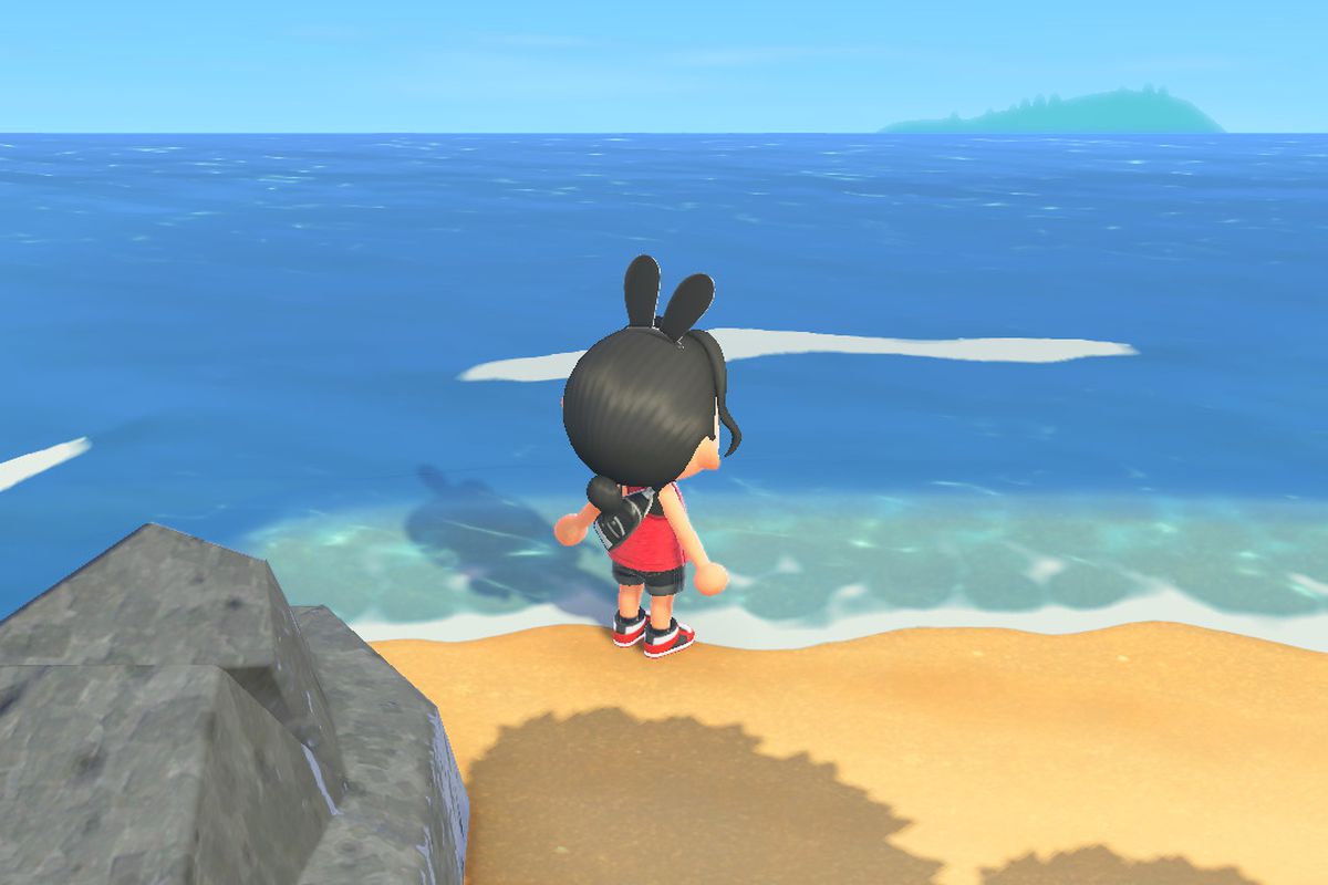 An Animal Crossing character stands on the small, secret beach area, facing the ocean