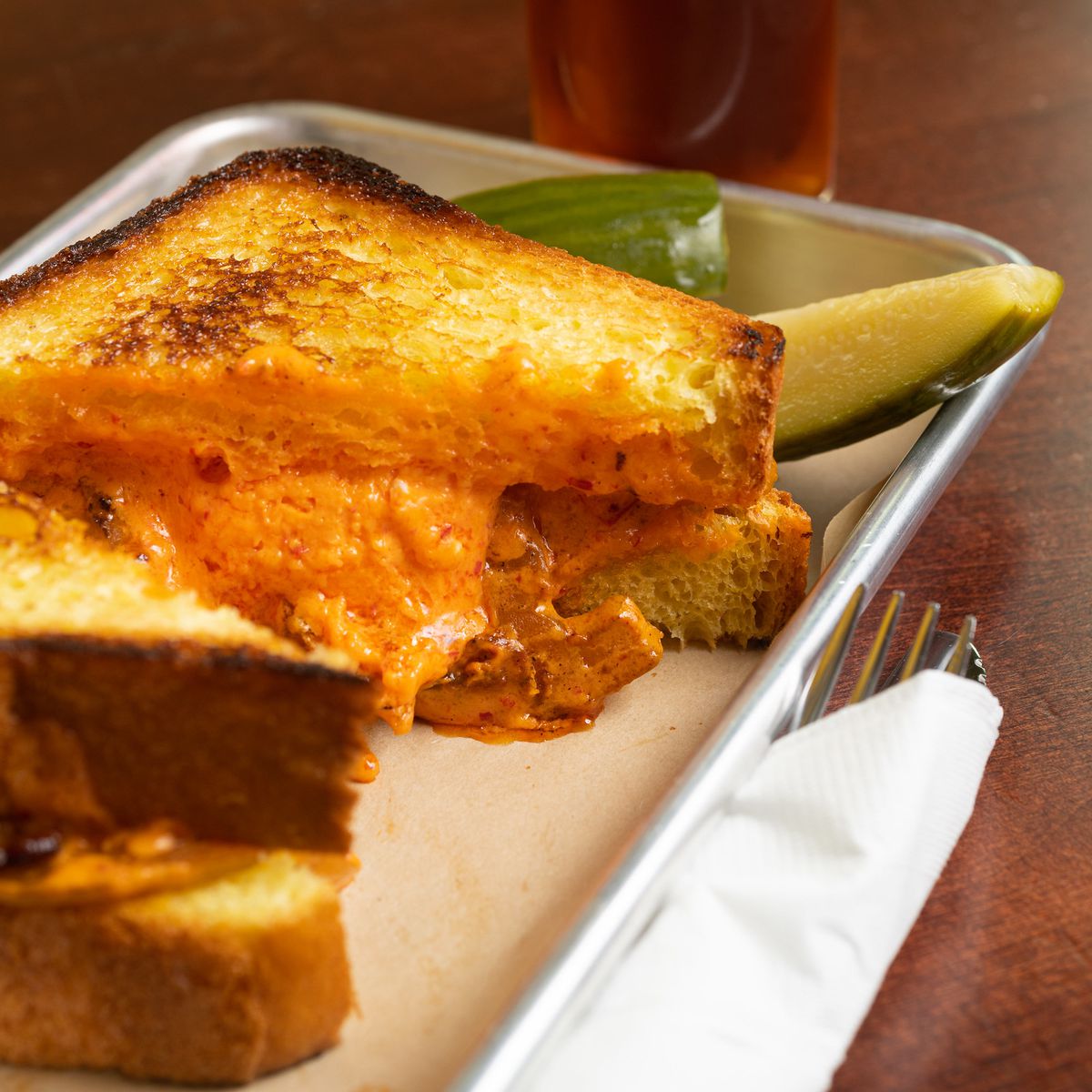 A grilled cheese sandwich. with a pickle slice.