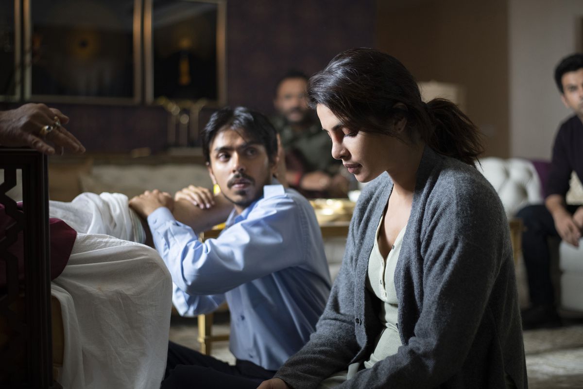 Adarsh ​​Gourav and Priyanka Chopra Jonas sit on the floor together in Netflix's THE WHITE TIGER