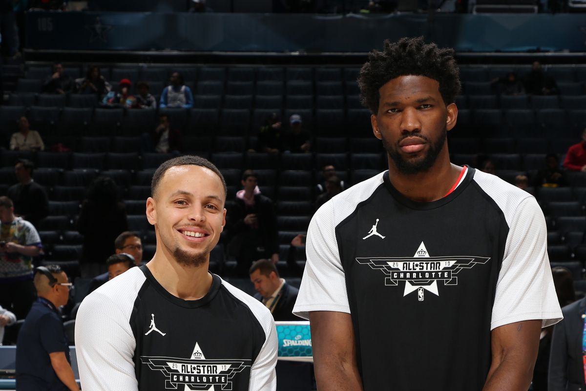 Steph Curry standing next to Joel Embiid in their All-Star warm-ups