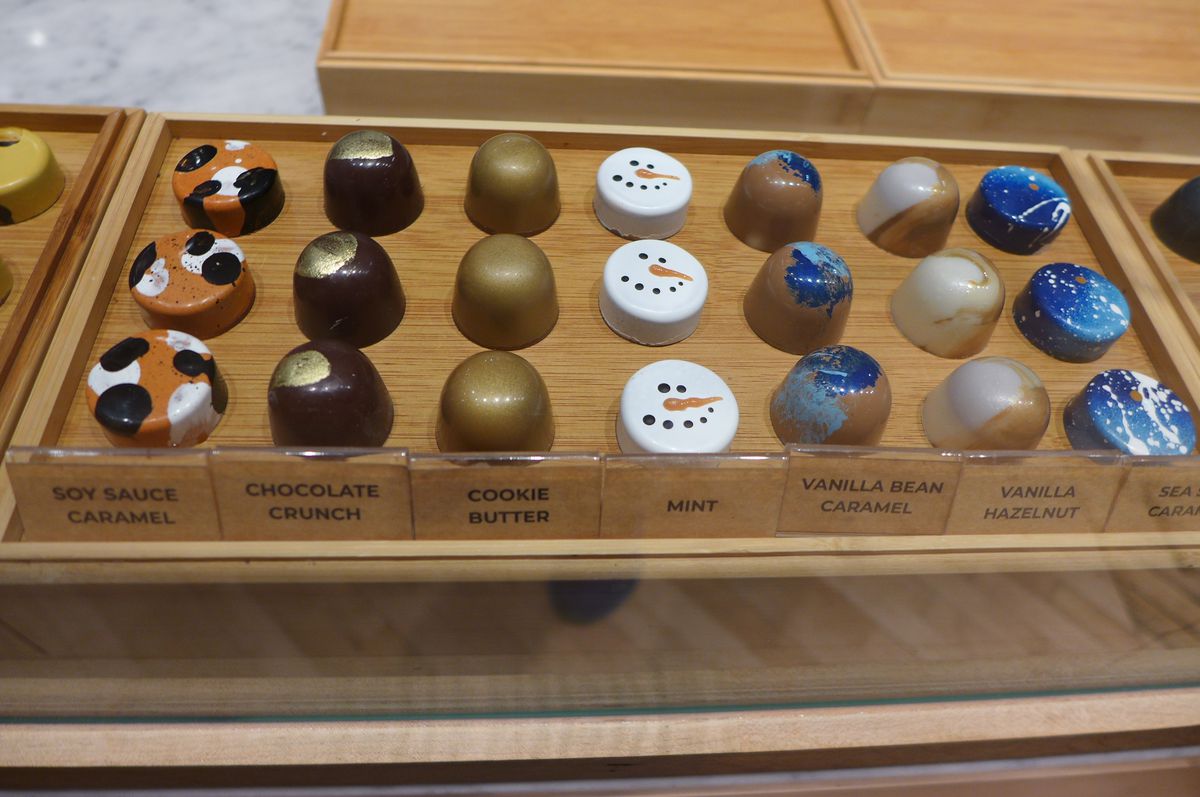 Seven colorfully painted chocolates, three each, in a wooden tray gleaming.
