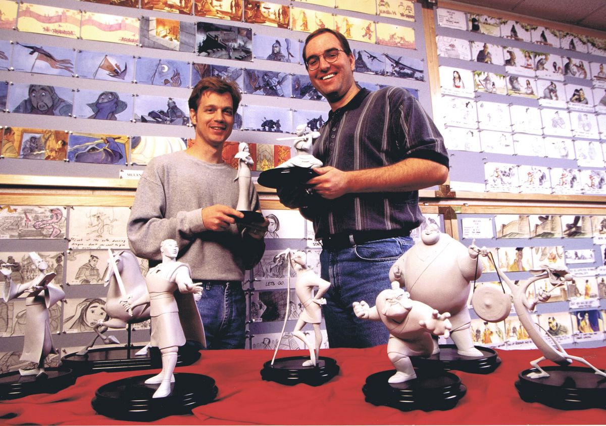 Disney's "Mulan" co-directors Barry Cook (left) and Tony Bancroft (right) stand surrounded by storyboards from the movie and maquettes of the characters. Circa 1998.