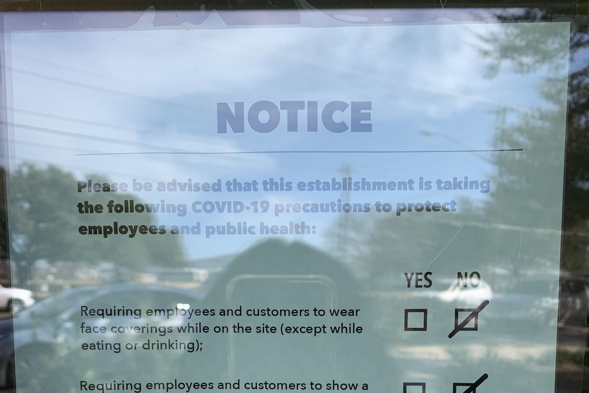 A sign behind a cafe window reading “Notice” and COVID-19 measures.