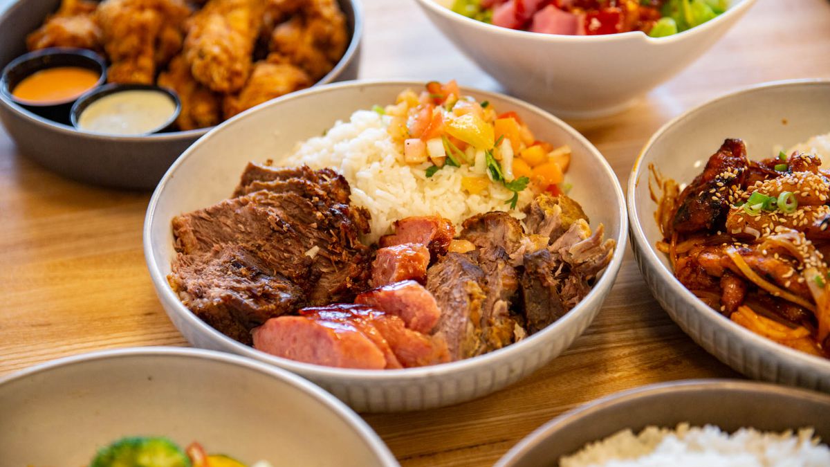 Several dishes from Tá Jóia restaurant, including Korean-style wings and a brisket, slow-cooked pork, and sausage medley with Spanish rice.