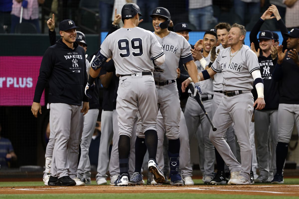 Aaron Judge #99 of the New York Yankees celebrates with teammates after hitting his 62nd home run of the season against the Texas Rangers during the first inning in game two of a double header at Globe Life Field on October 4, 2022 in Arlington, Texas.