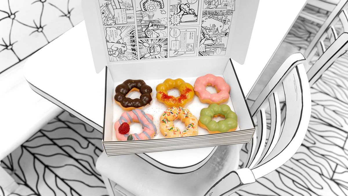 Six colorful mochi doughnuts inside a black and white box.