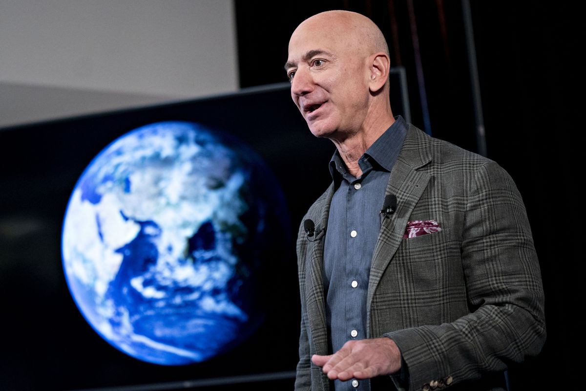 Jeff Bezos speaking onstage in front of a screen showing a picture of the Earth as seen from space.