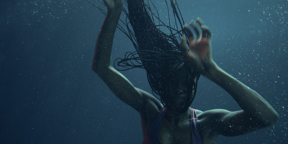 A woman submerged under water, her hair wafting upward in a sinuous collection of braids.