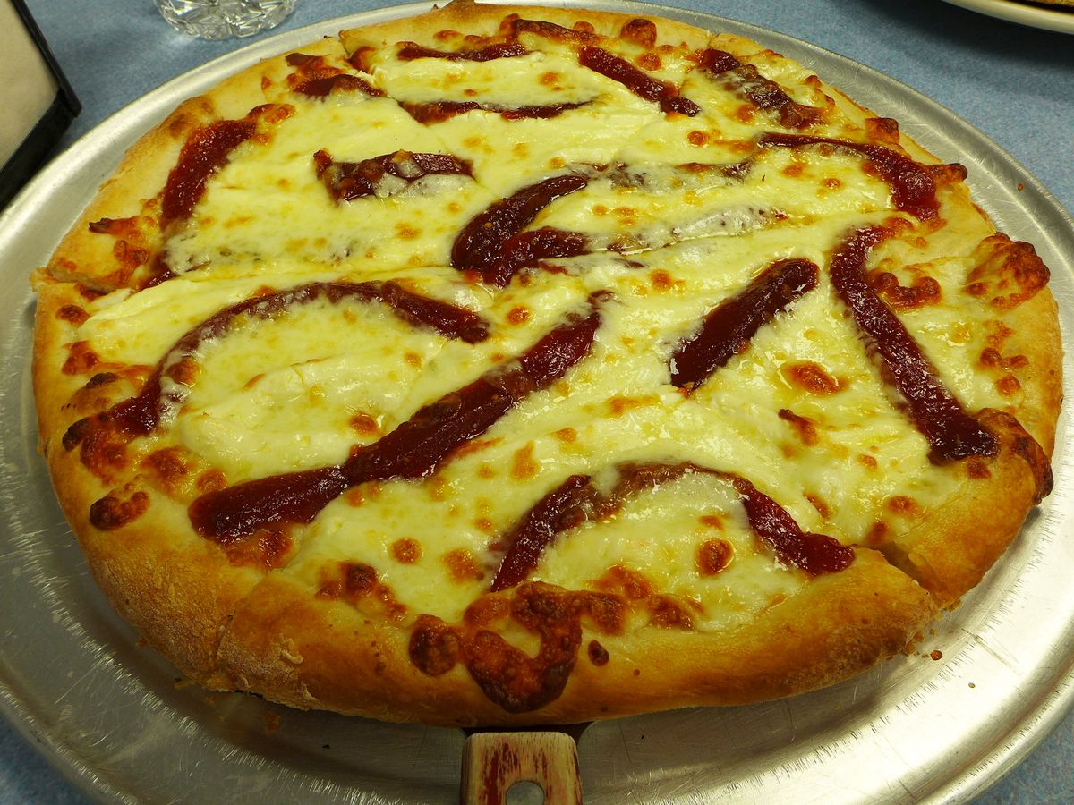 A round pizza features two kinds of cheese and squiggles of guava jam on top of the melted cheese