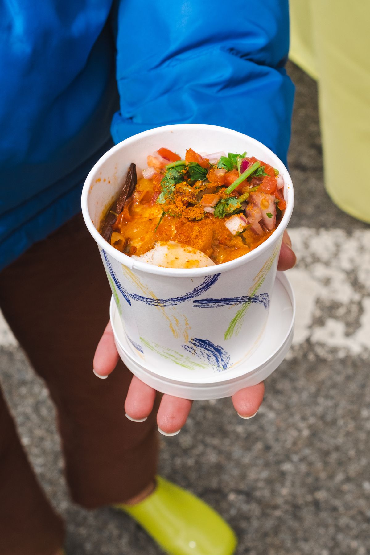 A hand holds a lentil dish in a container.