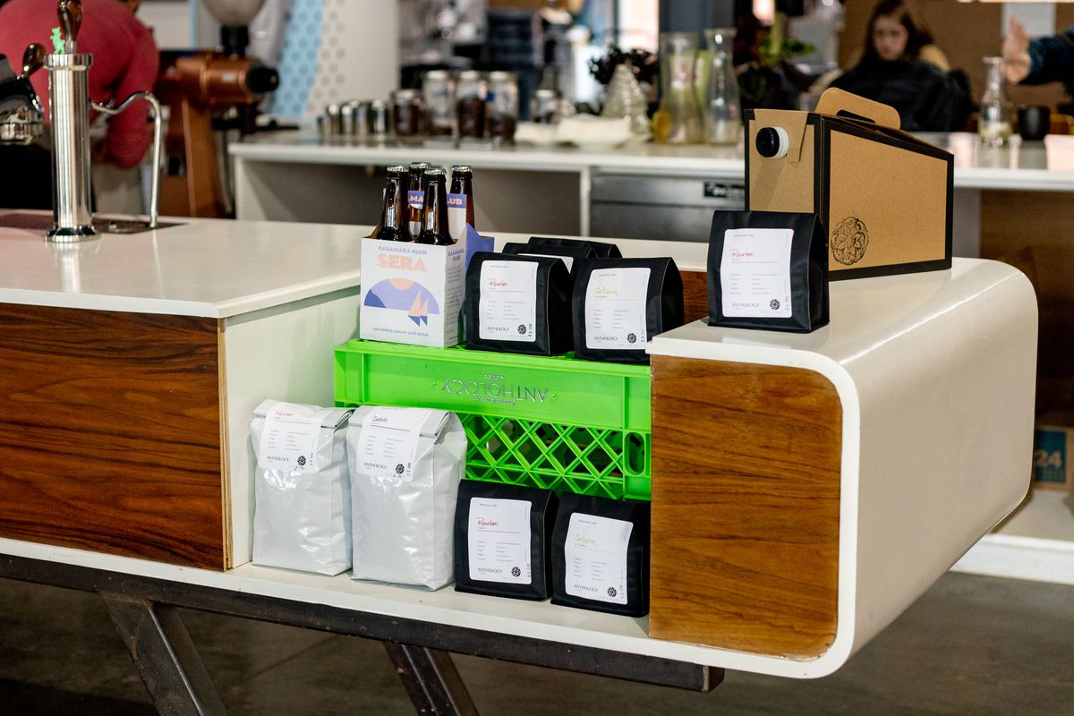 Bags of coffee at the white and wood paneled mid-century bar inside Anthology Coffee.